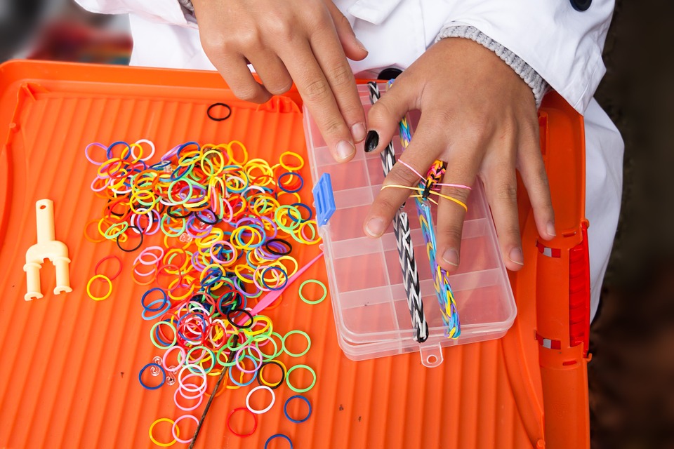 woman making a ring using rubber band in different colors.